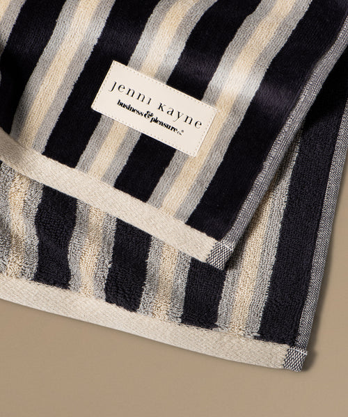Striped towel with a Jenni Kayne label on a beige background