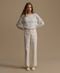 Woman wearing a striped shirt and beige pants against a beige background