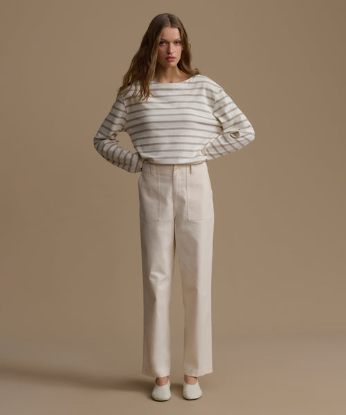 Woman wearing a striped shirt and beige pants against a beige background