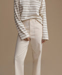 Person wearing a striped long-sleeve shirt and beige pants on a brown background