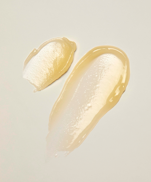 Two smears of Best-Selling Balm Duo, a translucent yellow-tinted hydrating balm, are shown on a light beige surface with a glossy texture and varying opacity.