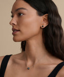 Woman with long wavy brown hair, in a black sleeveless top, wears the Philo Pearl Necklace and a pearl stud earring, shown in profile against a beige background.