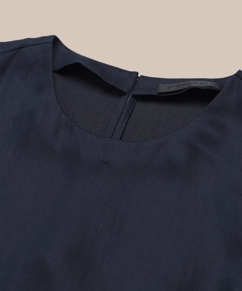 Close-up of the Blair Dress in navy blue, featuring a round neckline, hidden back zipper, and soft linen texture, displayed against a beige background.