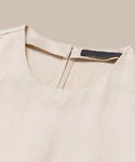 Close-up of the Blair Dress, a beige linen dress with a round neck, back zipper, and black label inside the collar, shown on a neutral background—perfect for updating your spring wardrobe.