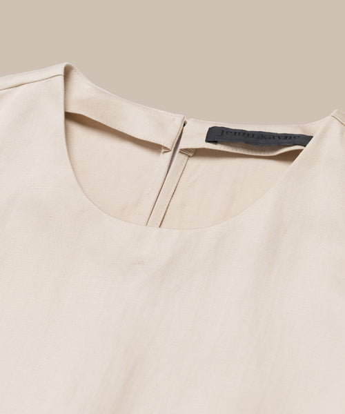 Close-up of the Blair Dress, a beige linen dress with a round neck, back zipper, and black label inside the collar, shown on a neutral background—perfect for updating your spring wardrobe.