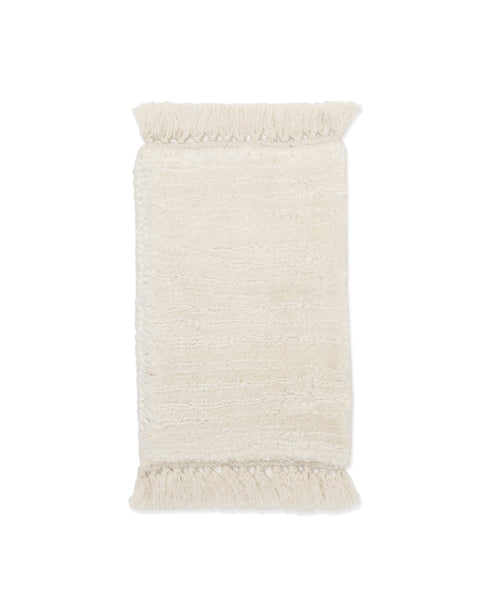A rectangular, off-white Rug Swatch in Bone with a textured finish and short fringe on both ends is shown on a plain white background.