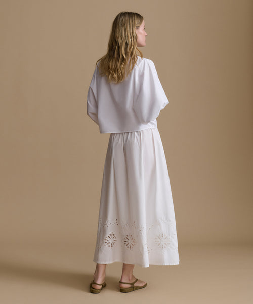 Woman wearing a white outfit with a beige background