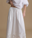 White blouse and skirt with intricate cut-out design on a beige background