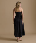 Woman wearing a black dress against a beige background