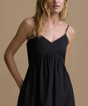 Woman wearing a black dress against a beige background