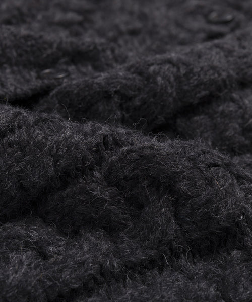 Close-up of dark gray or black knit fabric with a soft, fluffy texture and visible fibers, similar to the plush Peruvian yarn used in the Cable Juliette Cardigan.