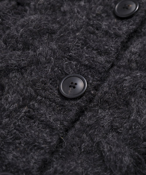 Close-up of the Cable Juliette Cardigan in dark gray, featuring a textured loose-knit pattern and large black buttons. The visible fibers enhance its cozy, inviting look.