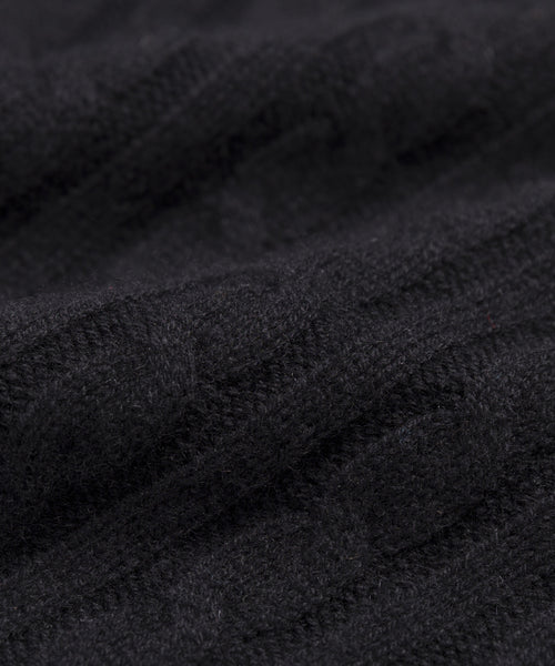 Close-up of the Cable Nell Turtleneck in black, highlighting its cozy cable knit texture and soft, slightly raised design that embodies classic turtleneck style.