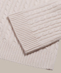 A close-up of the Cable Nell Turtleneck’s cream cable-knit sleeve over the body highlights ribbed cuffs, textured patterns, and its cozy boxy silhouette.