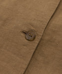 Close-up of a brown linen fabric with a single button fastened through a buttonhole, highlighting the texture and weave—showcasing the elegant details of the Callan Dress.