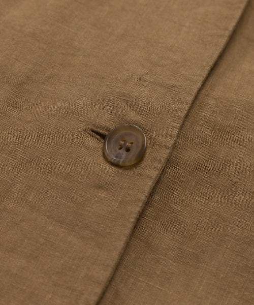 Close-up of a brown linen fabric with a single button fastened through a buttonhole, highlighting the texture and weave—showcasing the elegant details of the Callan Dress.
