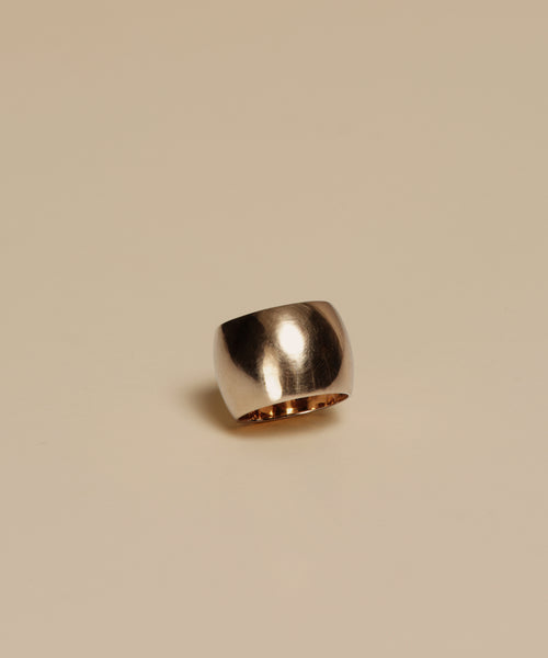 The Campbell Cigar Band, a wide and shiny 14k solid gold ring with a smooth finish, is shown against a plain beige background.