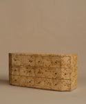 A six-drawer burlwood dresser in warm beige and brown tones, set against a solid beige background.