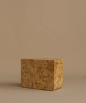 A burlwood nightstand with drawers, featuring natural burl wood grain and small dark metal knobs, set against a solid beige background.