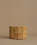 A burlwood nightstand with drawers, featuring natural burl wood grain and small dark metal knobs, set against a solid beige background.