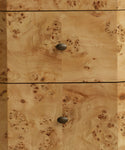 Close-up of a burl wood cabinet or drawer front with two dark oval knobs, showing rich tan and brown wood grain patterns.