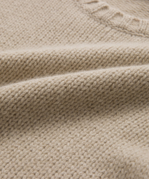 Close-up of the Cashmere Amelia Crewneck in beige, featuring a lightweight chunky knit with a textured pattern and ribbed neckline. The soft fabric and intricate weave create a cozy, elevated look.
