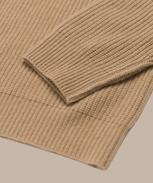 Close-up of the Cashmere Cocoon Cardigan in beige, highlighting its ribbed knit texture and pure cashmere fabric, with the sleeve folded neatly over the body to showcase luxurious detail.