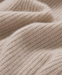 Close-up of soft, beige knit fabric with a ribbed texture. Gentle folds and fine fibers highlight the cozy warmth—ideal for the Cashmere Cocoon Cardigan, wrapping you in comfort.