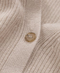 Close-up of the beige knit fabric of the Cashmere Cocoon Cardigan, featuring a single round tan button. The texture and stitching highlight the cardigans softness and detailed craftsmanship.