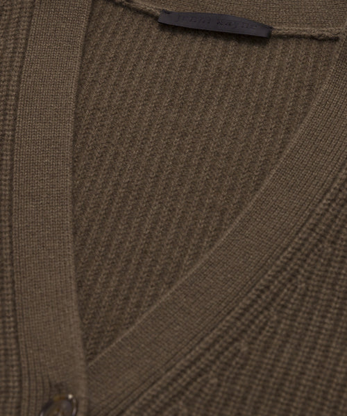 Close-up of the Cashmere Cocoon Cardigan, a brown ribbed knit oversized cashmere piece with a V-neck, single button closure, and a black label at the collar. The soft fabric’s texture is clearly visible.