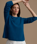 Woman wearing a blue cashmere sweater against a beige background