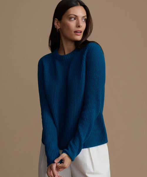 Woman wearing a blue cashmere sweater against a brown background