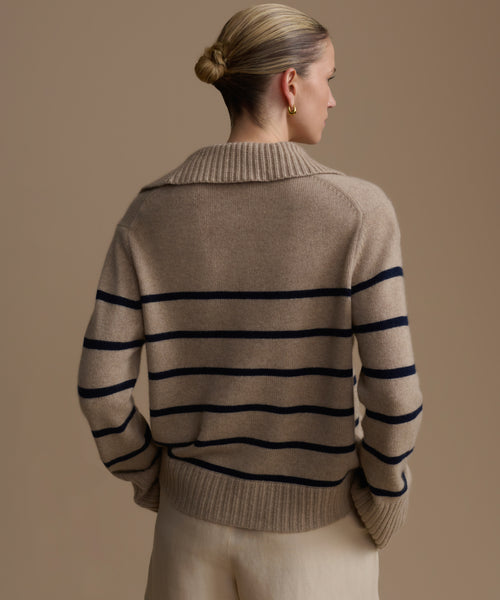 Woman wearing a beige cashmere sweater with black horizontal stripes against a beige background
