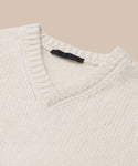 Close-up of the Cashmere Kate V-Neck sweater in ivory, featuring a ribbed collar and black neckline tag, set against a light beige background.