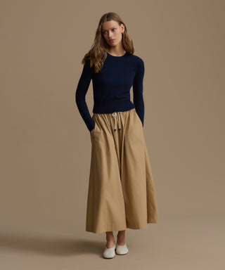 Woman wearing a Cashmere Leni Crewneck and beige wide-leg pants against a brown background