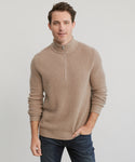 A man with short brown hair wears the Mens Wool Half Zip sweater in beige and dark jeans, standing against a light gray background. He smiles softly with his left hand by his side and his right hand touching his thigh.