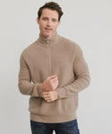 A man in a beige Mens Wool Half Zip and dark jeans stands against a light background, looking at the camera with a relaxed expression. The lightweight knit of the sweater creates an easy, casual style.