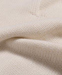 Close-up of the Cashmere Phoebe Polo in soft ivory, featuring a textured ribbed pattern and jersey-knit flexibility, gently folded to showcase its cozy, luxurious appearance.