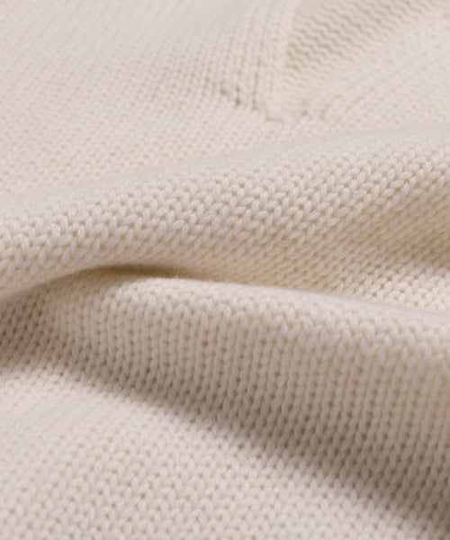 Close-up of the Cashmere Phoebe Polo in soft ivory, featuring a textured ribbed pattern and jersey-knit flexibility, gently folded to showcase its cozy, luxurious appearance.