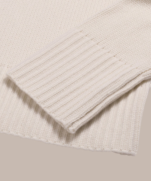 Close-up of the sleeve and hem of the Cashmere Phoebe Polo in ivory, highlighting ribbed cuffs and fine jersey-knit texture against a neutral background.