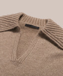 A close-up of the Cashmere Phoebe Polo—a women’s beige cashmere sweater with a wide ribbed collar and deep V-neck—laid flat on a light background.