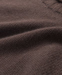 Close-up of brown knitted fabric with a ribbed edge, highlighting the texture and weave of the Cashmere Porter Turtleneck sweater.