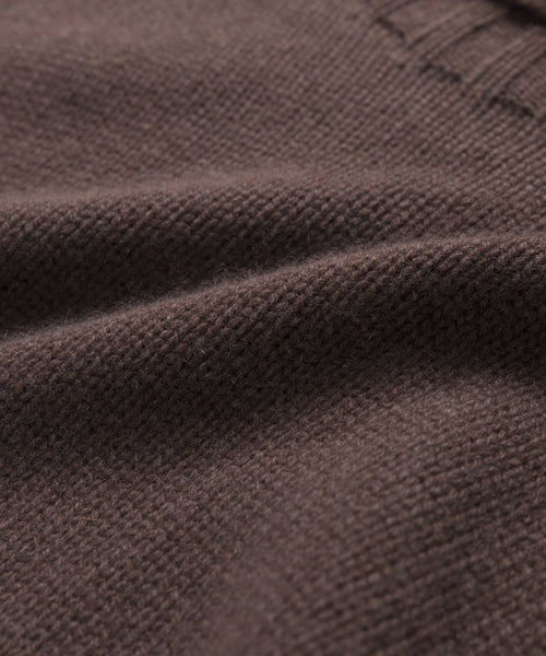 Close-up of brown knitted fabric with a ribbed edge, highlighting the texture and weave of the Cashmere Porter Turtleneck sweater.
