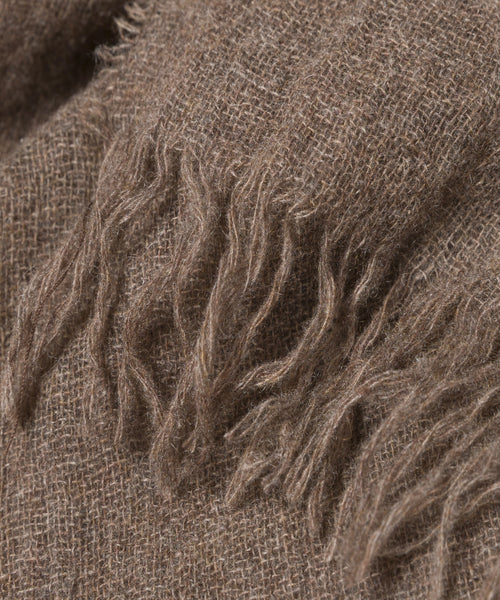 Close-up of a brown, lightweight Cashmere Shawl with a soft texture and loose, frayed fringe along the edge—ideal as a cozy travel scarf.