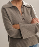 Model wearing sweater with ribbed, exaggerated collar, buttoned neck and bell sleeves.