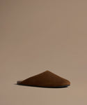 Brown leather mule against a beige background.