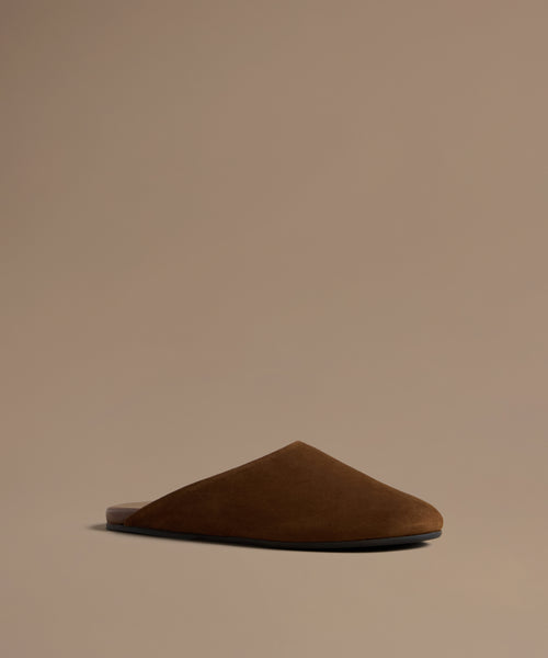 Brown leather mule against a beige background.