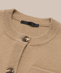Close-up of the Charlotte Cardigan, a camel women’s cardigan with brown buttons, ribbed crew neck, and a visible black label inside.