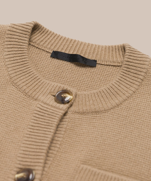 Close-up of the Charlotte Cardigan, a camel women’s cardigan with brown buttons, ribbed crew neck, and a visible black label inside.