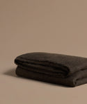 Folded chocolate alpaca throw on a beige background